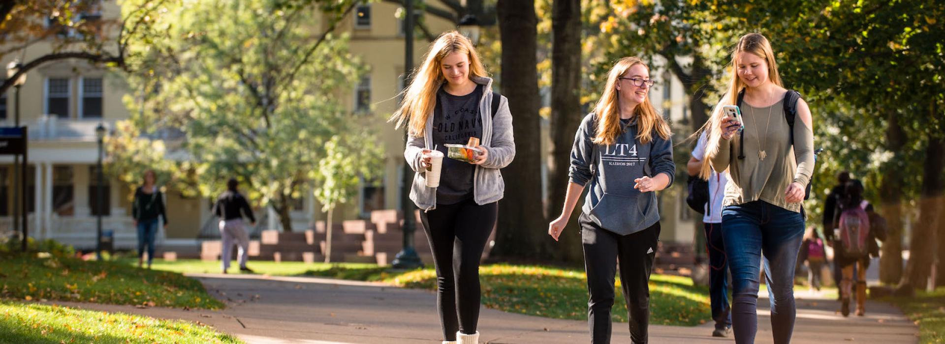 Three students walking through campus on a sunny fall day