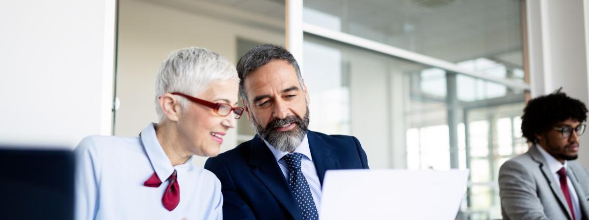A stock photo of two business professionals talking while sitting at a table.