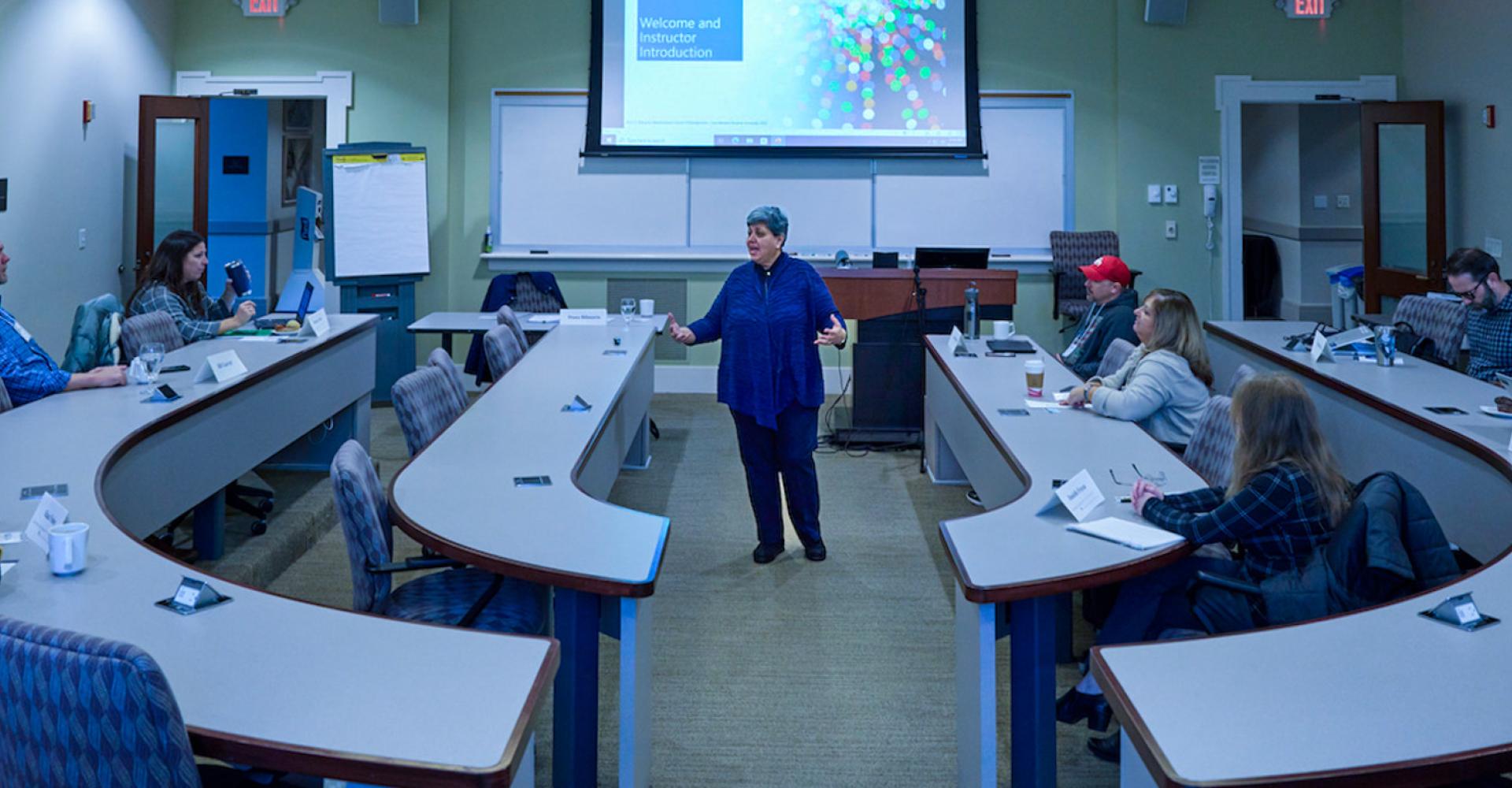 Wide shot of a classroom of students watching Diana Bilimoria lecture in the middle-front of the room
