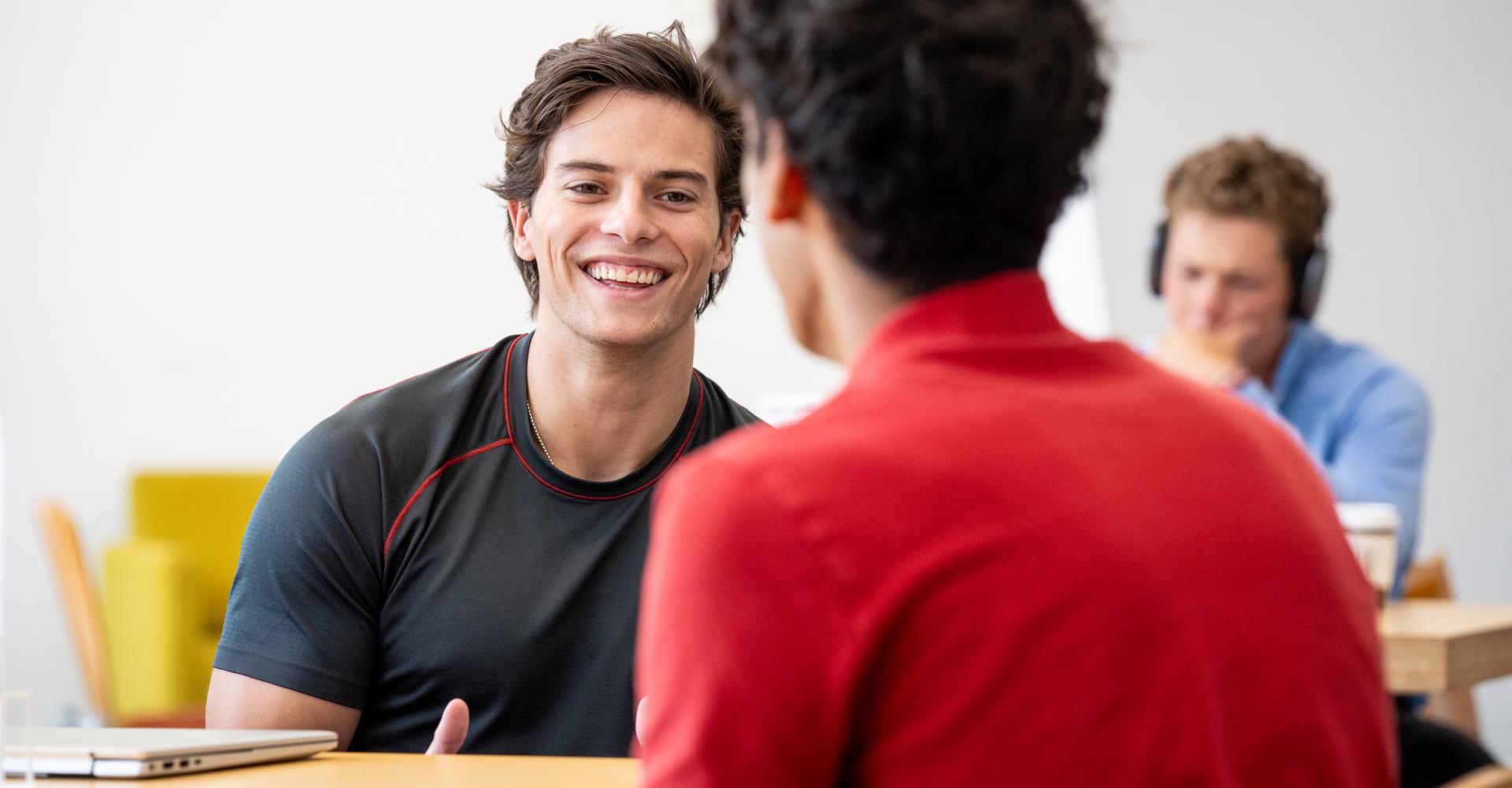 Male students sitting at tables conversing