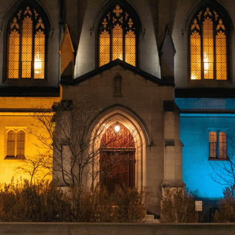 Photograph of Amasa Stone Chapel’s exterior at night and lit in blue and yellow