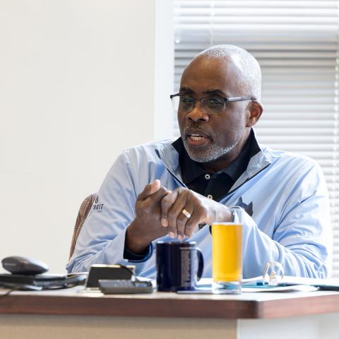 Professor sitting as a desk speaking