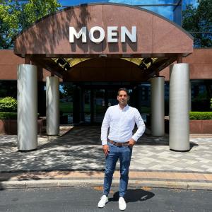 Photo of Samit Chauhan posing outside a building labeled "MOEN"