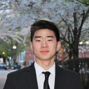 Darren Wang smiles in a black suit.