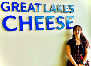 Nishitha Laveti stands in front of Great Lakes Cheese sign