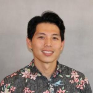 Rich Fong smiles in a floral shirt against a grey background.