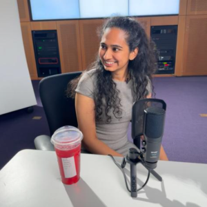 Disha Hegde smiles while sitting next to a microphone.