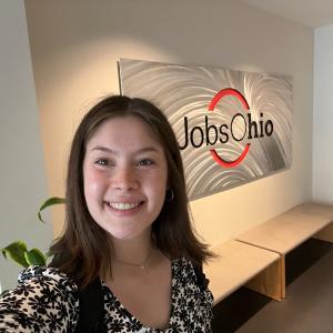 Katie Merritt smiles in a selfie in front of a JobsOhio sign in her office.