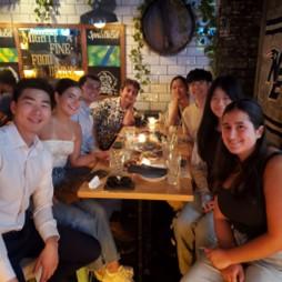 A group of students sitting a table in a dimly-lit social setting