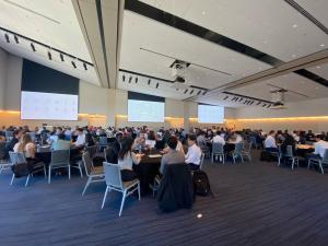 Wide-angle photograph of a large meeting room full of tables, where students are meeting with accounting firms