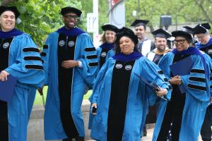 Faculty and students entering the 2025 commencement from outdoors
