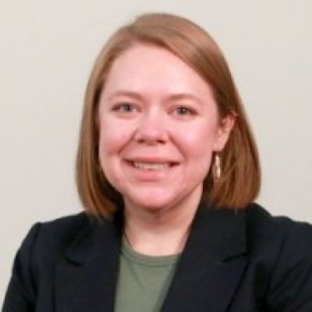 Sara Donnelly smiles in a black suit.