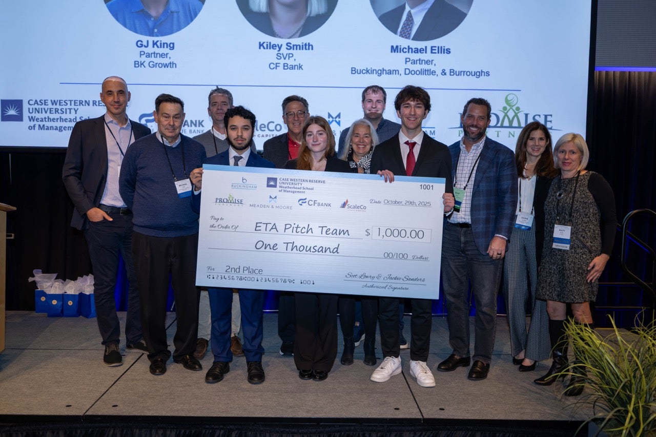 A group of students and presenters stand on a stage holding a large, $1,000 second-place prize check awarded to the "ETA Pitch Team" at a Case Western Reserve University event.