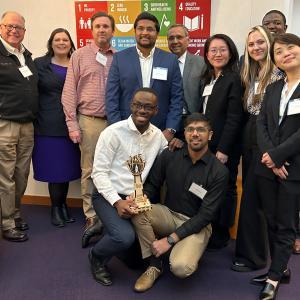 Impact investment Competition first place team smiles with trophy and judges