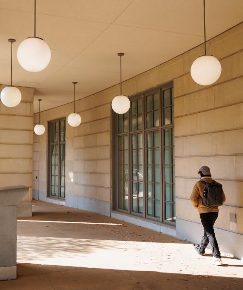 View from behind of a student walking through a lit outdoor building passage