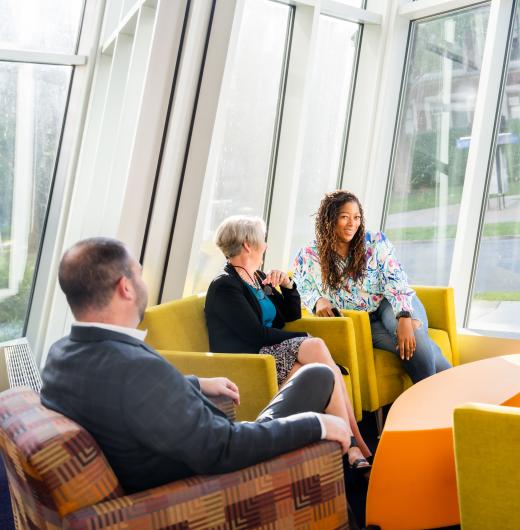 Students and teachers sitting in yellow chairs