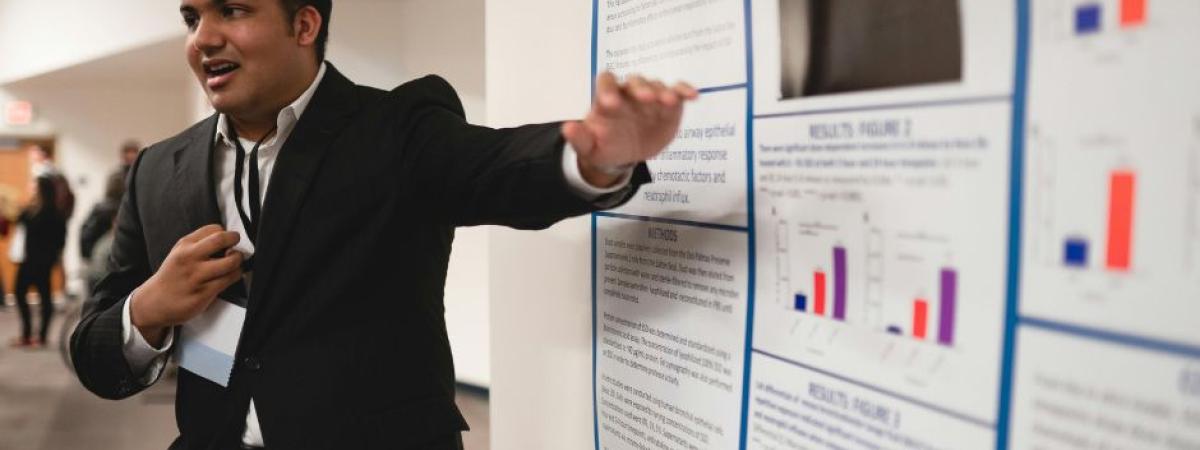 Male student showing off poster presentation