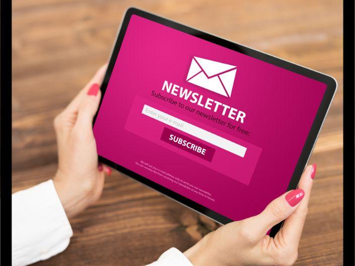 Hands holding an iPad that says "Newsletter" and "Subscribe"
