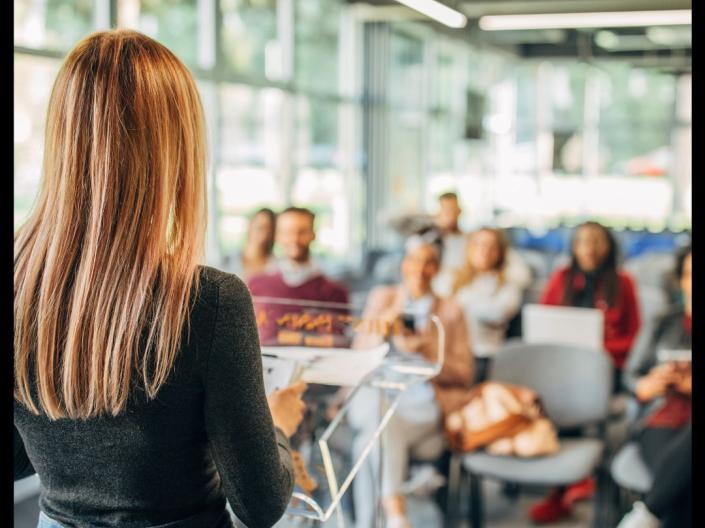 A woman speaking to a group in a classroom setting