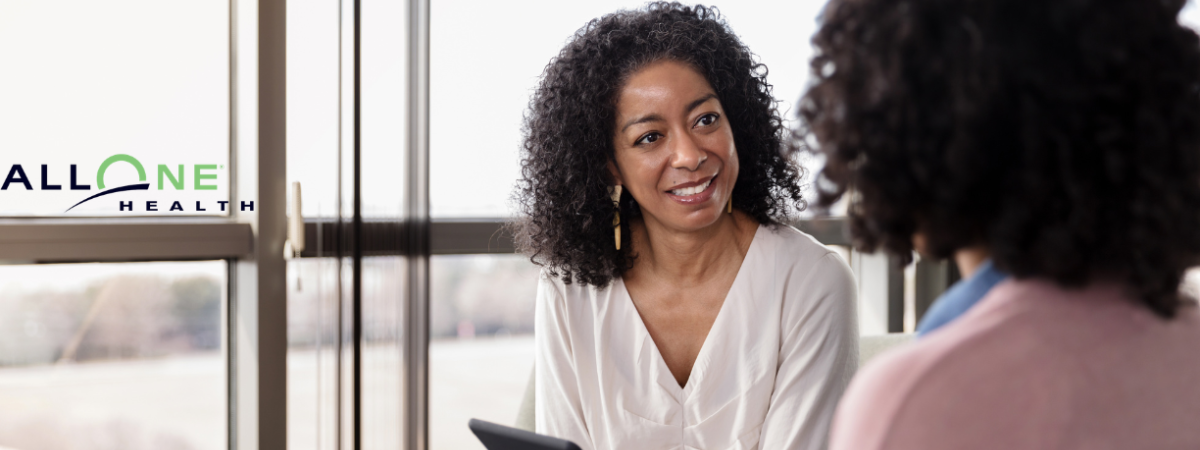 Photo of a counseling session taking place between two people, featuring the AllOne Health logo