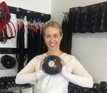 Photo of Logan Jacklin holding an exercise ball and standing in front of other exercise equipment