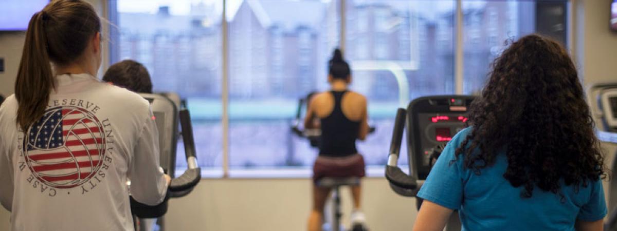 Three women with backs to camera using exercise bikes in CWRU's Wyant Center