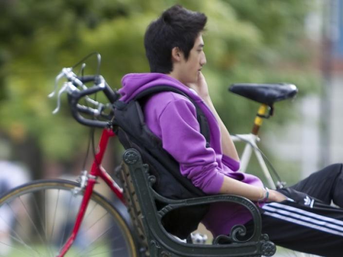 A male Case Western Reserve University student sitting next to a bike