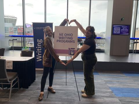 Two undergraduates pose with a sign advertising the NE Ohio Writing Programs